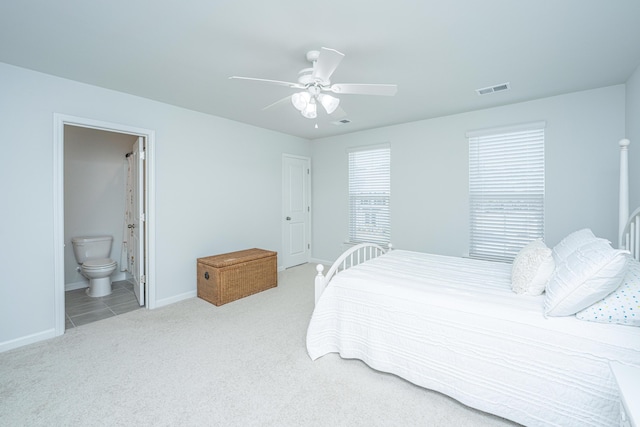 bedroom featuring visible vents, baseboards, a ceiling fan, ensuite bath, and carpet