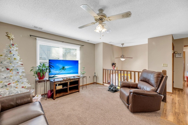 living room with carpet, ceiling fan, and a textured ceiling