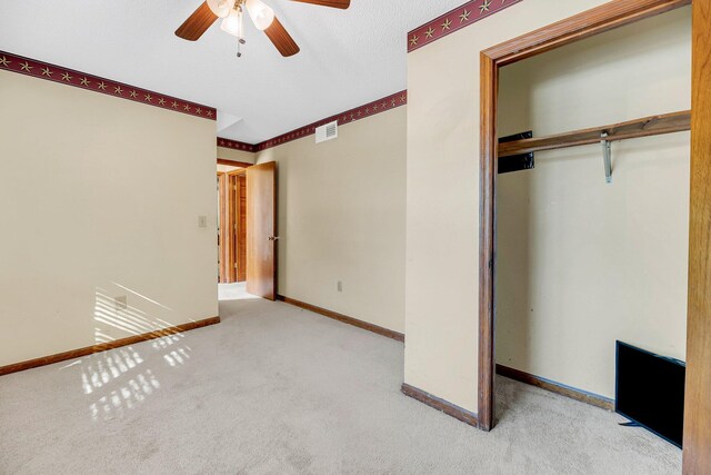 unfurnished bedroom featuring light carpet, a closet, and ceiling fan