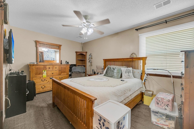 bedroom featuring ceiling fan, dark carpet, and a textured ceiling