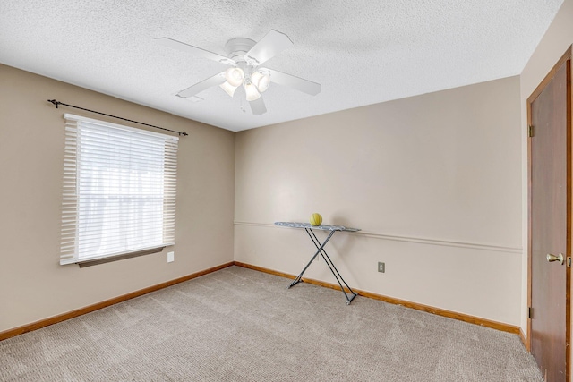 carpeted empty room with ceiling fan and a textured ceiling