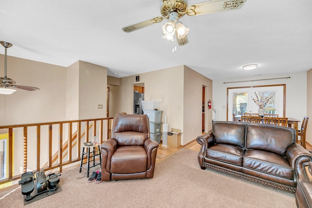 living room with ceiling fan, carpet floors, and a textured ceiling