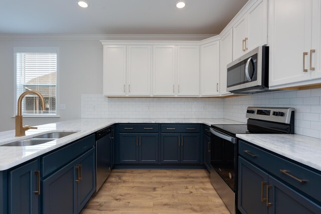 kitchen with light hardwood / wood-style floors, decorative backsplash, white cabinetry, ornamental molding, and sink