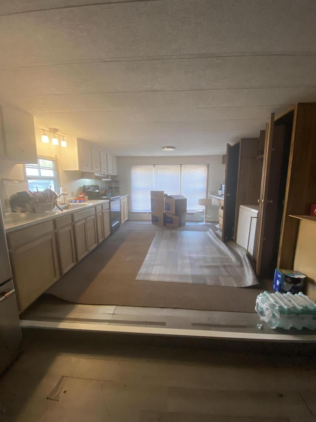 kitchen with light countertops, freestanding refrigerator, electric range oven, and a sink