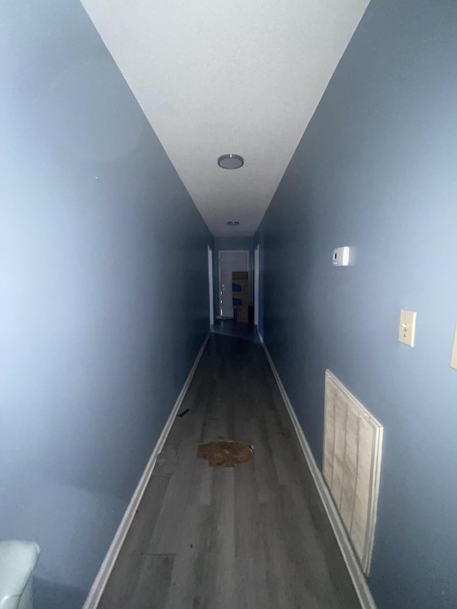 corridor featuring baseboards and wood finished floors