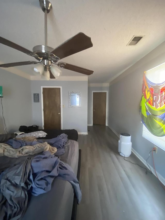 bedroom featuring visible vents, baseboards, wood finished floors, and a ceiling fan