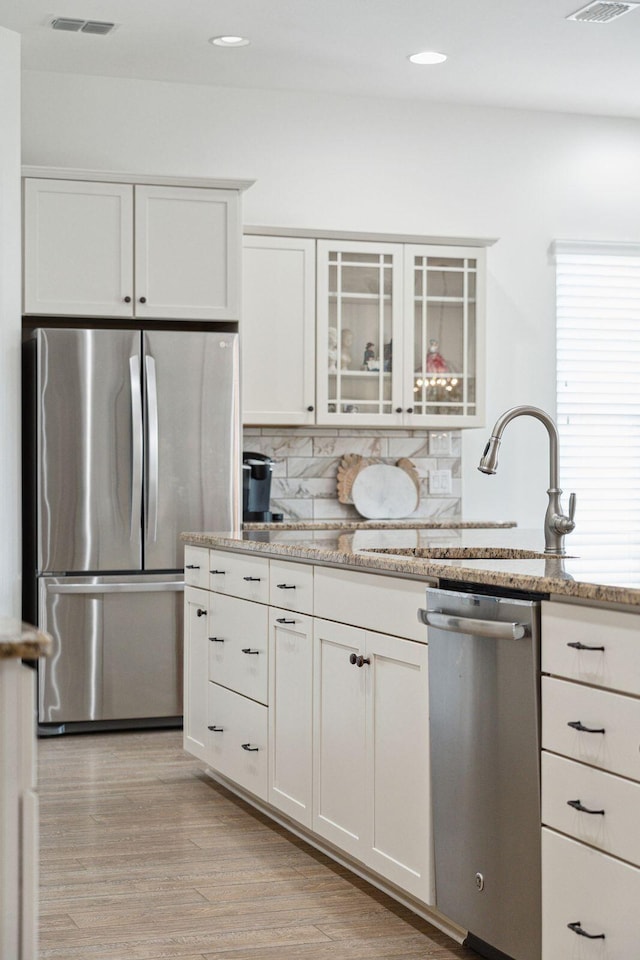 516 Tidewater Chase Ln, Summerville, SC 29486 - kitchen featuring appliances with stainless steel finishes, a sink, white cabinetry, light wood-style flooring, and light stone countertops