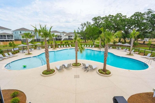 community pool featuring fence, a residential view, and a patio