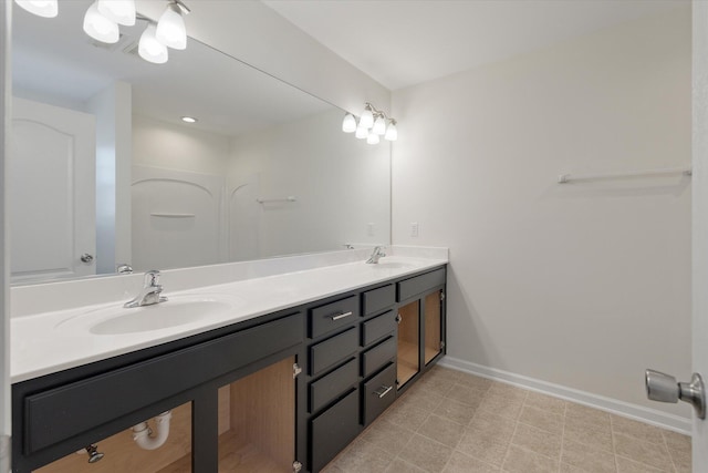 full bath featuring double vanity, baseboards, and a sink