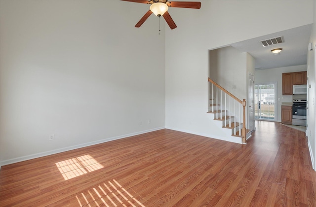 unfurnished living room featuring light wood-style floors, baseboards, stairs, and visible vents