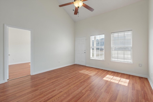 unfurnished room featuring baseboards, high vaulted ceiling, ceiling fan, and light wood-style floors