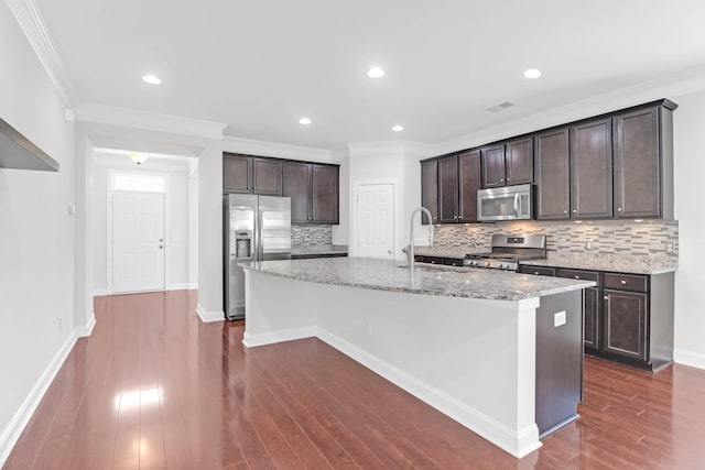 kitchen with stainless steel appliances, a sink, light stone counters, and dark brown cabinetry