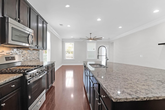 kitchen with tasteful backsplash, appliances with stainless steel finishes, dark wood-type flooring, crown molding, and a sink