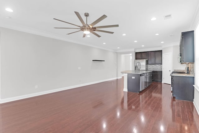 kitchen featuring a kitchen island with sink, dark wood-type flooring, baseboards, tasteful backsplash, and crown molding