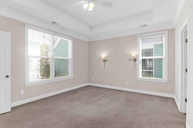 carpeted spare room featuring a raised ceiling, visible vents, and baseboards