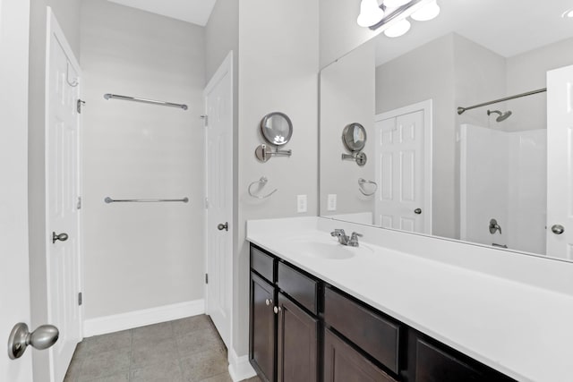 bathroom with a shower, tile patterned floors, vanity, and baseboards