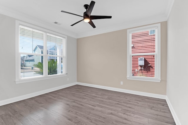 empty room with baseboards, ceiling fan, wood finished floors, and crown molding