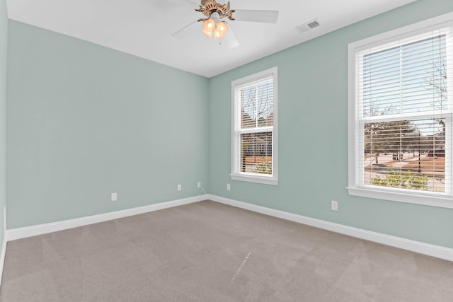 carpeted empty room with visible vents, plenty of natural light, and baseboards