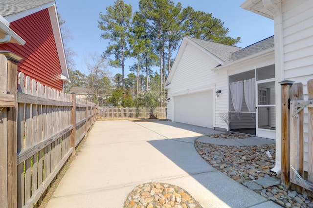 exterior space featuring driveway, an attached garage, fence, and a shingled roof