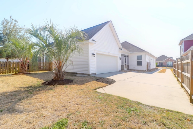 view of front of house featuring a garage, driveway, fence, and a front yard