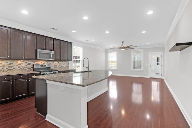 kitchen featuring appliances with stainless steel finishes, a sink, decorative backsplash, and ornamental molding