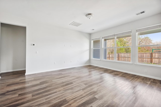 spare room featuring wood finished floors, visible vents, and baseboards