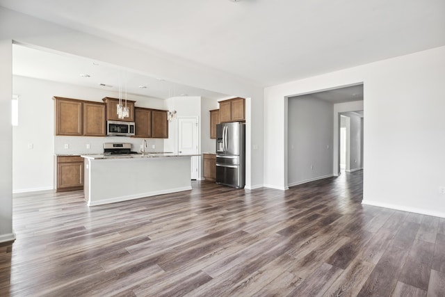 unfurnished living room featuring dark wood-type flooring, a sink, and baseboards