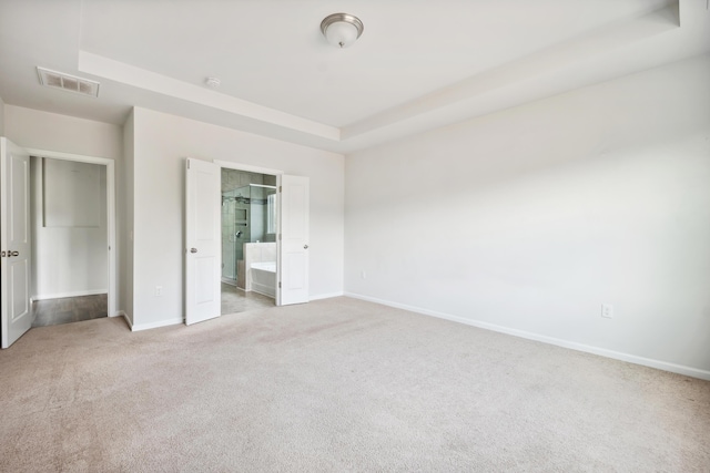 unfurnished bedroom with a tray ceiling, baseboards, visible vents, and carpet