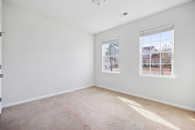 empty room featuring carpet floors, visible vents, and baseboards