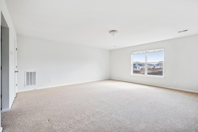 spare room featuring carpet, visible vents, and baseboards