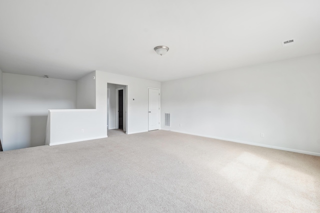 unfurnished room with visible vents, light carpet, and baseboards