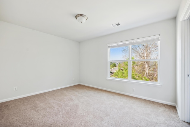 empty room featuring carpet floors, visible vents, and baseboards