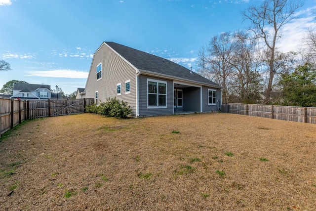 back of house featuring central air condition unit, a fenced backyard, and a yard