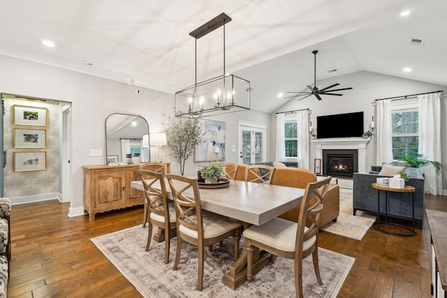 dining space featuring vaulted ceiling, dark wood-type flooring, and ceiling fan with notable chandelier