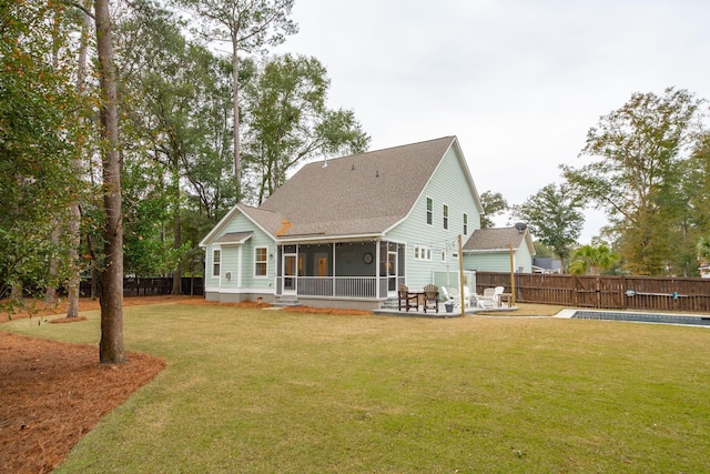 rear view of house featuring a sunroom, a patio area, a yard, and a swimming pool