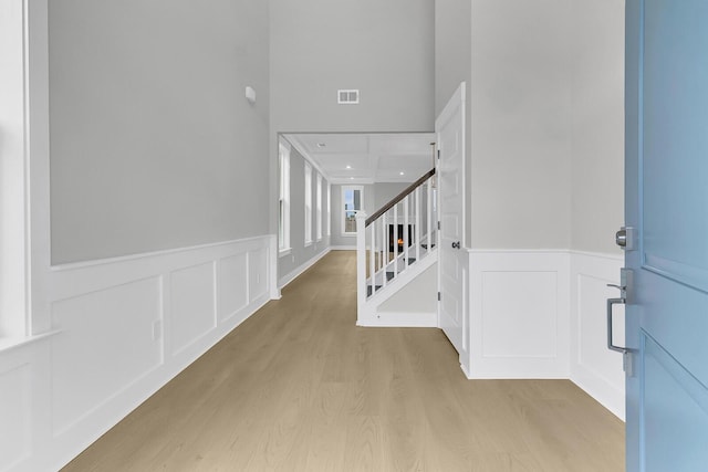 entryway with visible vents, wainscoting, stairway, wood finished floors, and a decorative wall