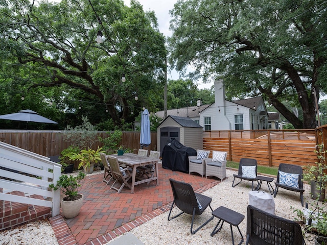 2 Live Oak Ave, Charleston, SC 29407 - view of patio / terrace with a fenced backyard, grilling area, outdoor dining area, a storage unit, and an outbuilding