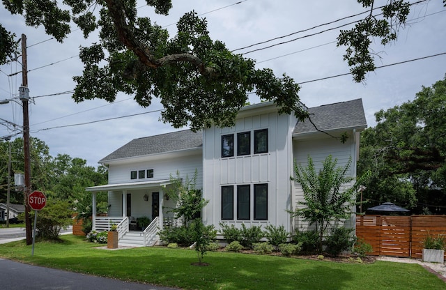 2 Live Oak Ave, Charleston, SC 29407 - modern farmhouse style home featuring board and batten siding, covered porch, a front yard, fence, and a shingled roof