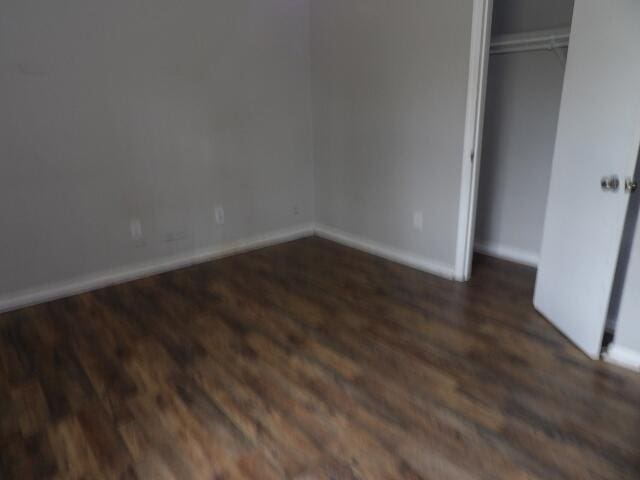 unfurnished bedroom featuring wood finished floors, baseboards, and a closet