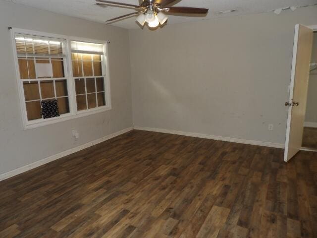 empty room with a ceiling fan, baseboards, and dark wood-style flooring