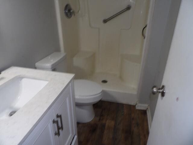 bathroom featuring wood finished floors, toilet, a shower, and vanity