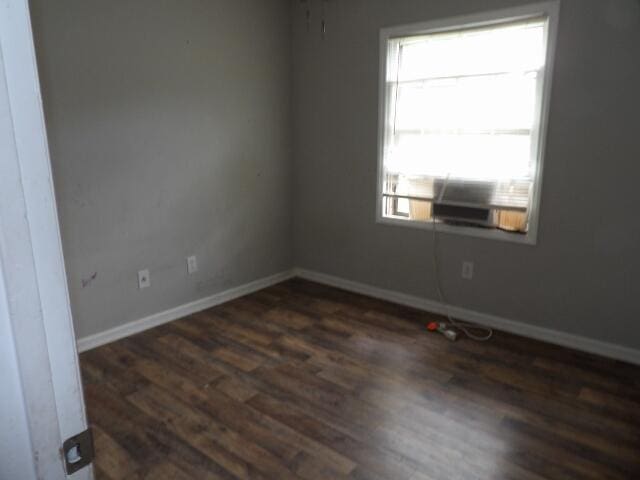 spare room with dark wood-style flooring and baseboards