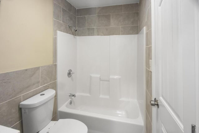 bathroom with washtub / shower combination, tile walls, and toilet