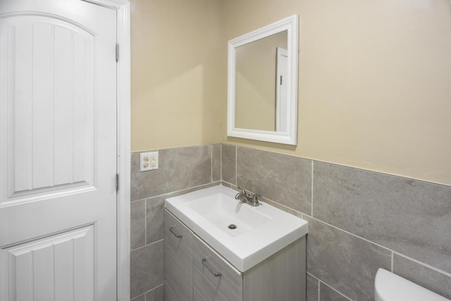 bathroom with tile walls, toilet, and vanity