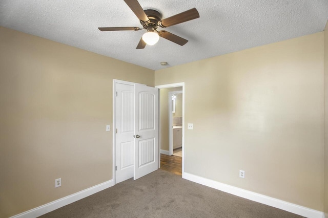 empty room with a textured ceiling, dark colored carpet, and ceiling fan