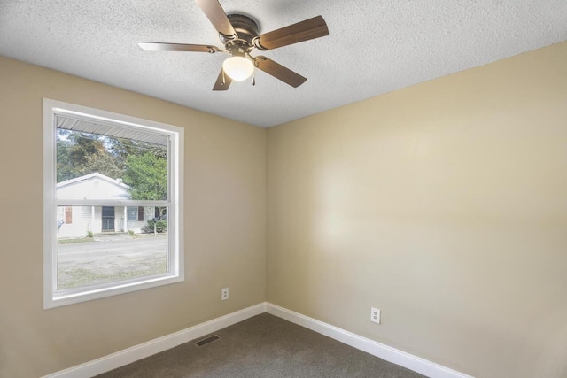 unfurnished room featuring a textured ceiling, dark colored carpet, ceiling fan, and a wealth of natural light