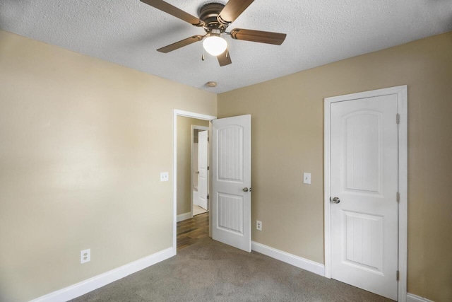 unfurnished bedroom with a textured ceiling, ceiling fan, and dark carpet