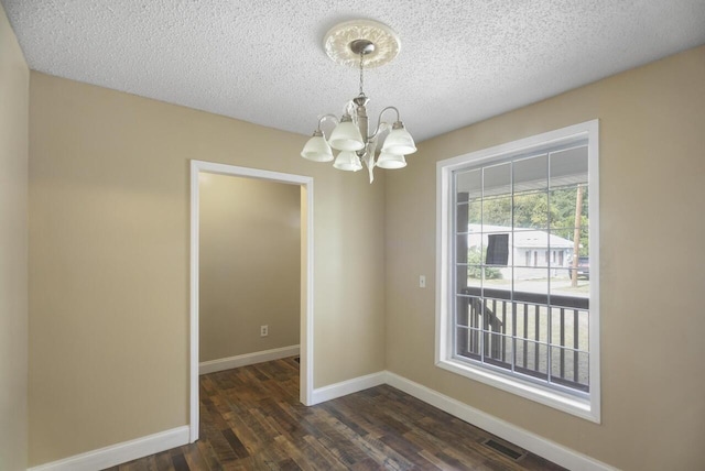 unfurnished room with a chandelier, a textured ceiling, and dark hardwood / wood-style flooring