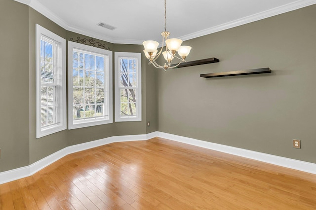 spare room with hardwood / wood-style flooring, crown molding, and a chandelier