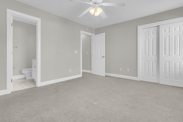 unfurnished bedroom featuring light carpet, ceiling fan, a closet, and ensuite bath